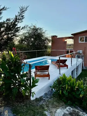 a deck with a swimming pool and two chairs at Clomplejo MUNAY con piscina y parking in Villa Cura Brochero