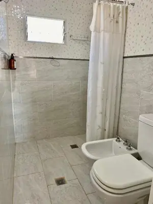a white bathroom with a toilet and a shower at Clomplejo MUNAY con piscina y parking in Villa Cura Brochero