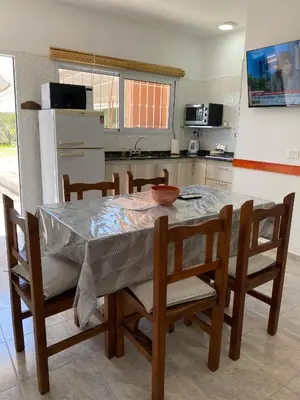a kitchen with a table and chairs and a kitchen with a refrigerator at Clomplejo MUNAY con piscina y parking in Villa Cura Brochero