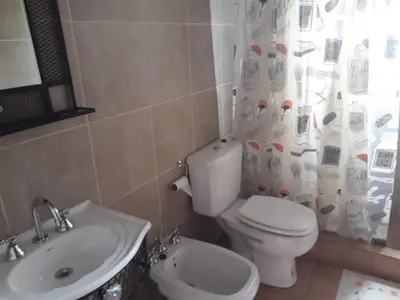 a bathroom with a toilet and a sink and a shower curtain at Cabaña Sombra Lunar en Cabañas Encuentro in Carpintería