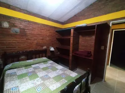 a bedroom with a bed and a brick wall at Alojamiento temporal mis seis soles in Villa de Las Rosas