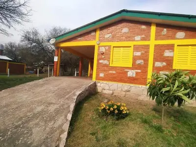 a house with yellow shutters and flowers in front of it at Alojamiento temporal mis seis soles in Villa de Las Rosas