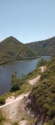 a lake with a dirt road next to a mountain at Karylago11 in San Roque