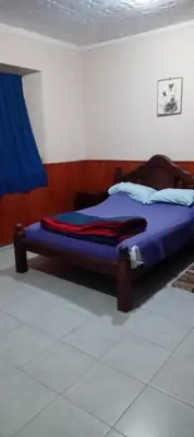 a bedroom with a bed with purple sheets and a blue curtain at Karylago in Casa Bamba