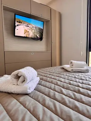 a bedroom with a bed with towels and a flat screen tv at Bahía 108 Apart Premium in Villa Carlos Paz