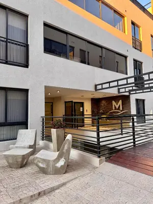 a building with two chairs in front of it at Bahía 108 Apart Premium in Villa Carlos Paz