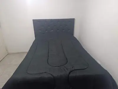 a black bed sitting in a corner of a room at Celeste departamento in Cordoba
