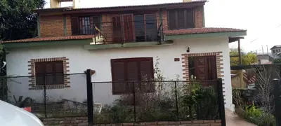 a white house with red windows and a fence at Sol y rio in Villa Carlos Paz