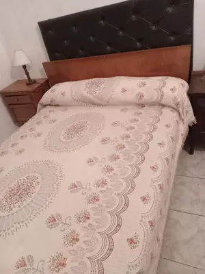a bed with a white comforter with a black headboard at Sol y rio in Villa Carlos Paz