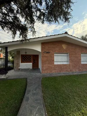 a brick house with a white bench in front of it at Chalet Pino azul in Villa Carlos Paz
