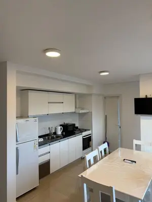 a kitchen with a table and a white refrigerator at Edificio Leonardo Villa Carlos Paz in Villa Carlos Paz