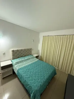 a bedroom with a bed with a green comforter at Edificio Leonardo Villa Carlos Paz in Villa Carlos Paz