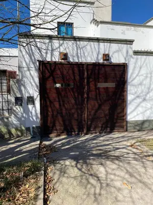 a large brown garage door on a white building at La moora in Alta Gracia