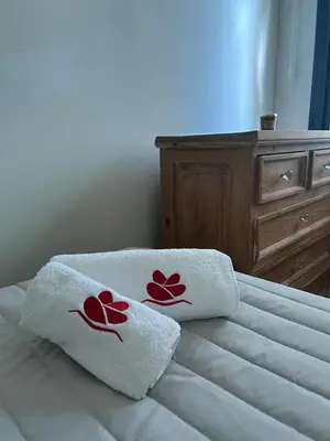 two towels with red flowers are sitting on a bed at Casa Frida - Alojamiento exclusivo para Mujeres - in Villa Carlos Paz