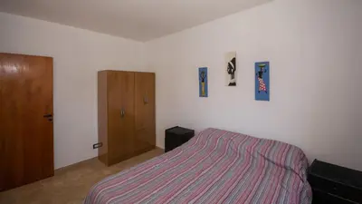 a bedroom with a bed and a wooden cabinet at Cabaña El Candil Solo Familias in Villa Carlos Paz