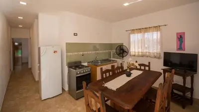 a kitchen with a table and a stove and a refrigerator at Cabaña El Candil Solo Familias in Villa Carlos Paz