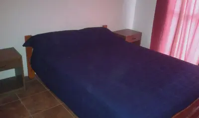 a blue bed in a bedroom with a red curtain at Los Damascos in Merlo