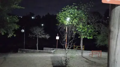 a park at night with a tree and a bench at Luluara in Villa Carlos Paz