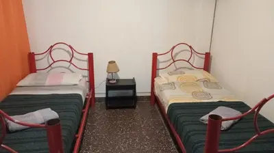 two twin beds in a small room with a lamp at Luluara in Villa Carlos Paz