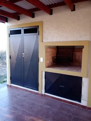 a house with two large doors and a patio at Complejo de Cabañas Los Virreyes in Cerro de Oro