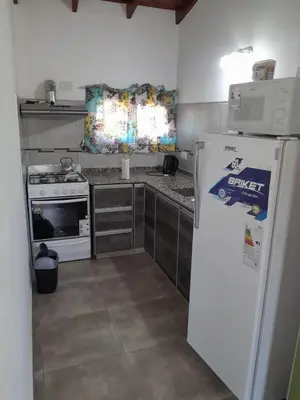 a kitchen with a white refrigerator and a stove at Complejo de Cabañas Los Virreyes in Cerro de Oro