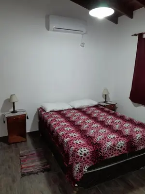 a bedroom with a bed with a red comforter at Complejo de Cabañas Los Virreyes in Cerro de Oro