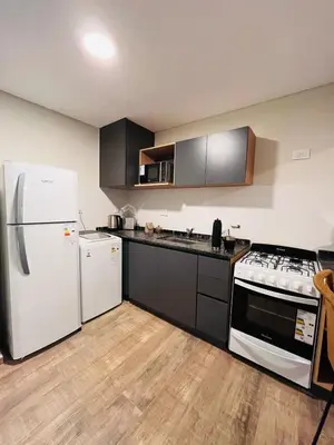 a kitchen with black cabinets and white appliances at Guarida Güemes in Cordoba