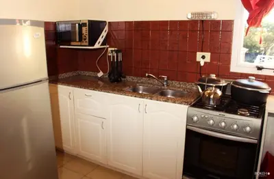 a kitchen with a sink and a stove and a refrigerator at Posada de las Sierras in Merlo