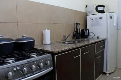 a kitchen with a stove and a sink and a refrigerator at Posada de las Sierras in Merlo