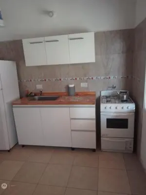 a kitchen with white cabinets and a stove at cabañas neli in Santa Rosa de Calamuchita