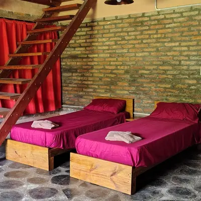 two beds with red sheets in a room with a staircase at La Casa Azul in San Javier