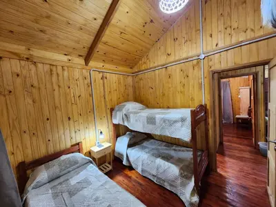 a room with three beds in a wooden cabin at Rincon Soñado in La Porteña