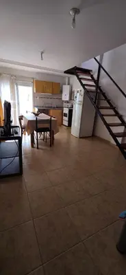 a living room with a kitchen and a staircase at La Martina in Villa Carlos Paz