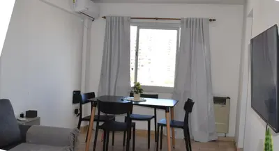 a living room with a table and chairs and a window at Departamento Abril in Cordoba