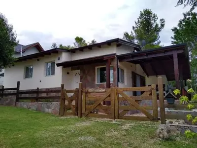 a house with a wooden gate and a fence at Casa Manantiales in Villa General Belgrano
