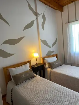 a bedroom with two beds and a wall with leaves painted on it at Casa Manantiales in Villa General Belgrano