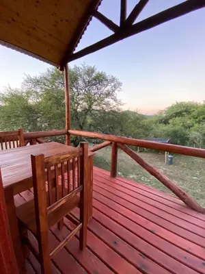 a wooden deck with a table and two chairs on it at CUYEN LA SERRANITA Dormi DLX Cabin para 2 Personas in Villa Serranita