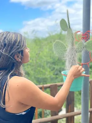 a woman holding a plant in a blue pot at CUYEN LA SERRANITA Dormi DLX Cabin para 2 Personas in Villa Serranita