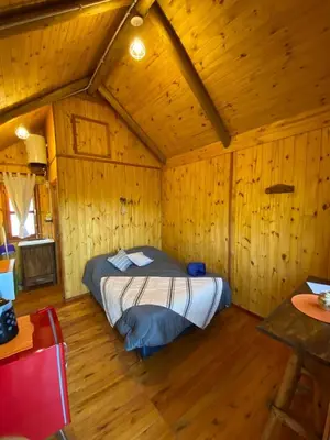 a bedroom with a bed in a wooden room at CUYEN LA SERRANITA Dormi DLX Cabin para 2 Personas in Villa Serranita