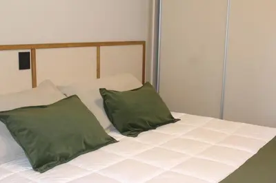 a white bed with two green pillows on it at Faz Flat in Cordoba