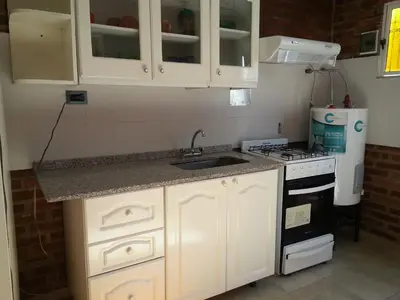a kitchen with white cabinets and a sink and a stove at Cabañassoleado Villa Cura Brochero in Villa Cura Brochero