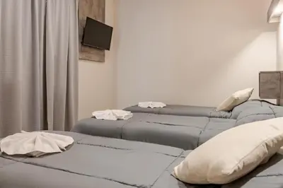 two beds in a room with a tv on the wall at Brit Hotel in Villa Carlos Paz