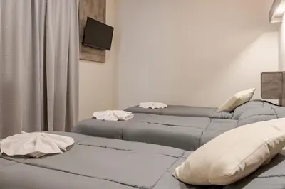 two beds in a room with a tv on the wall at Brit Hotel in Villa Carlos Paz