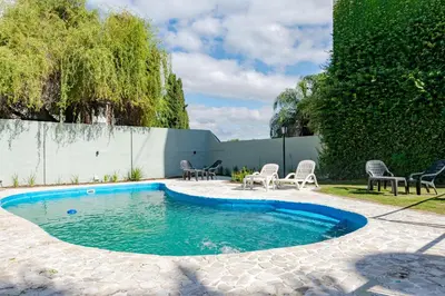 a swimming pool in a yard with chairs around it at Brit Hotel in Villa Carlos Paz