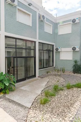 a blue house with glass windows and a driveway at Brit Hotel in Villa Carlos Paz