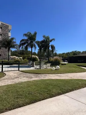 a park with a fence and grass and palm trees at Departamento Complejo Privado Mai Tei in Cordoba