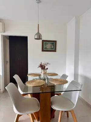 a dining room with a glass table and white chairs at Departamento Complejo Privado Mai Tei in Cordoba