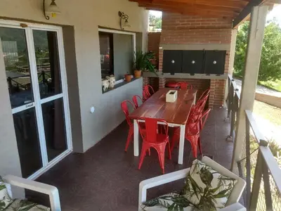 a patio with a wooden table and red chairs at Casa Serrana Mirador del Lago - Casa con Quincho in Bialet Massé