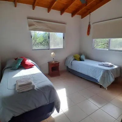 two beds in a room with two windows at Cabañas Amaneciendo in Merlo