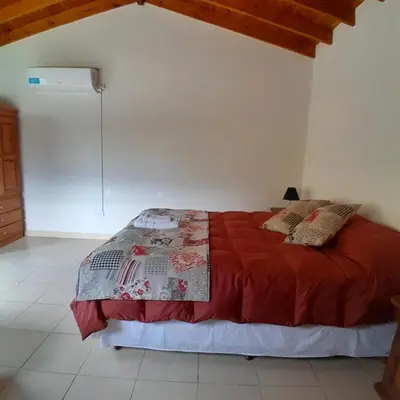 a bedroom with a bed with a red comforter at Cabañas Amaneciendo in Merlo